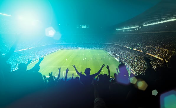 A football stadium with fans standing up cheering