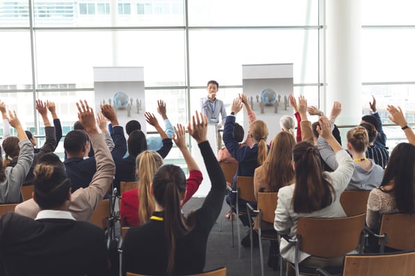 People raising their hands in a corporate seminar or workshop