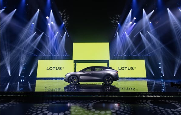 Silver Lotus Eletre on stage during the launch, with lights shining down on it and yellow Lotus branding behind it