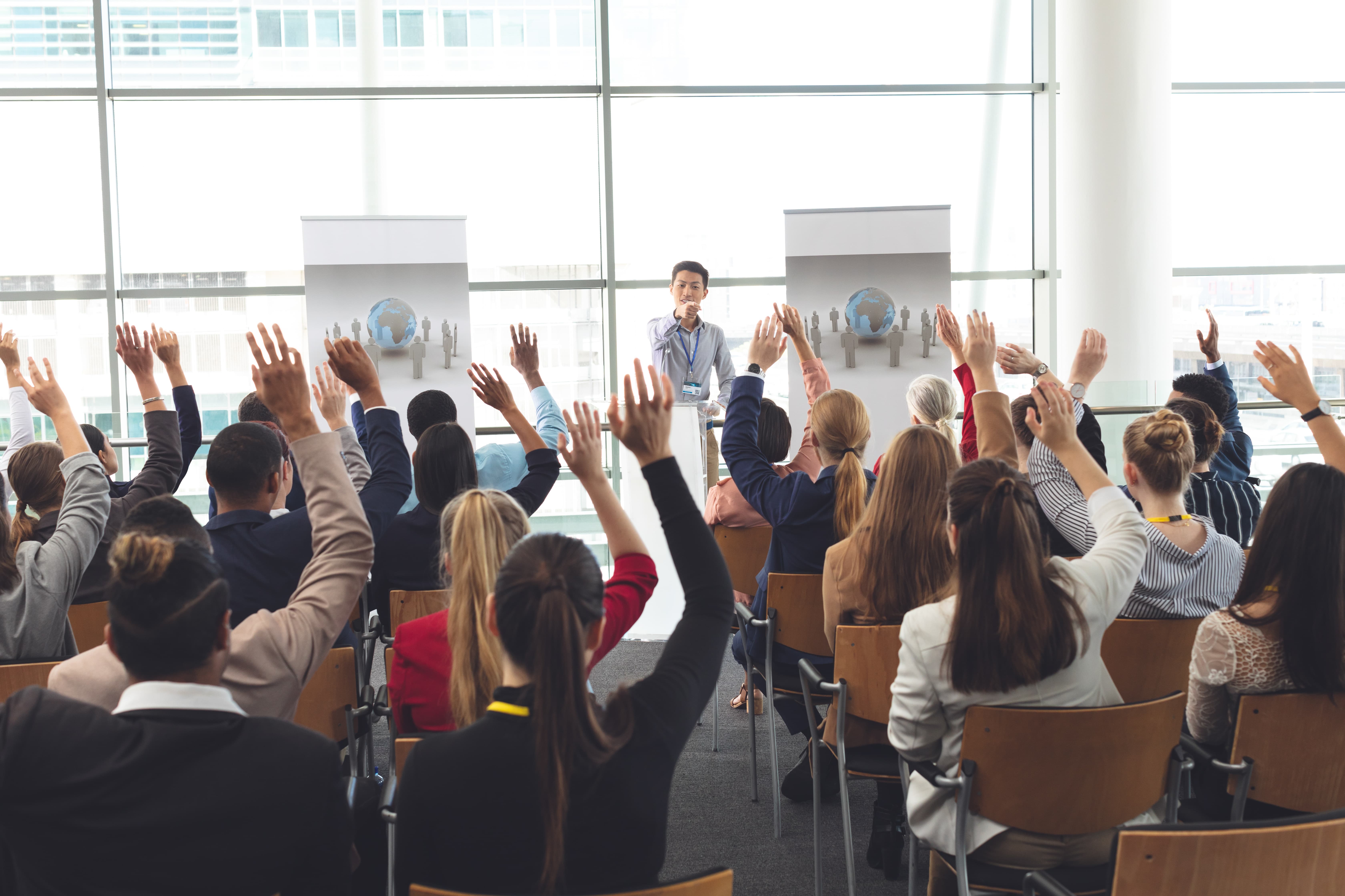 People raising their hands in a corporate seminar or workshop